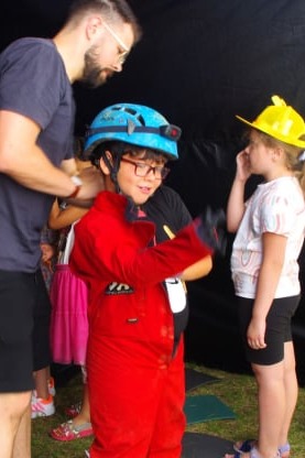 Kind probiert Anzug und Helm für Höhlenforschung an